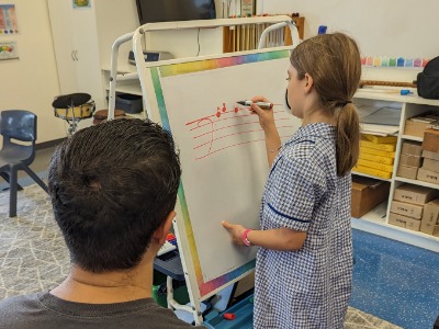 Teacher and student practising guitar together during one-on-one music lesson
